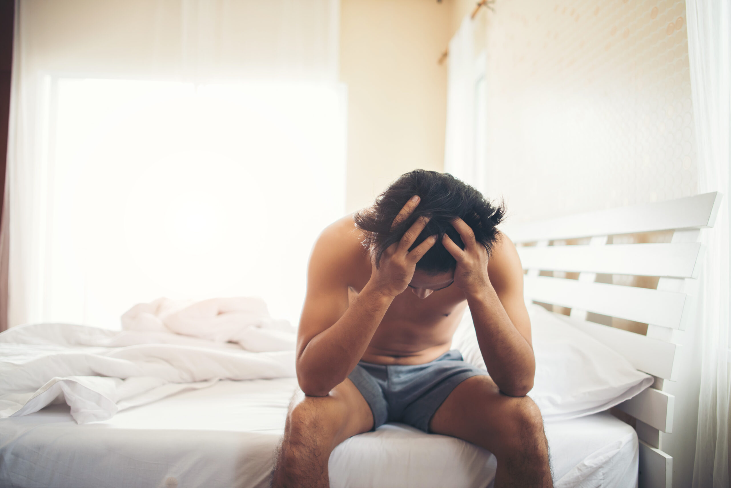 worried man sitting on bed in the morning, serious thinking some